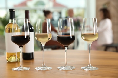 Photo of Bottles and glasses with different wines on table against blurred background