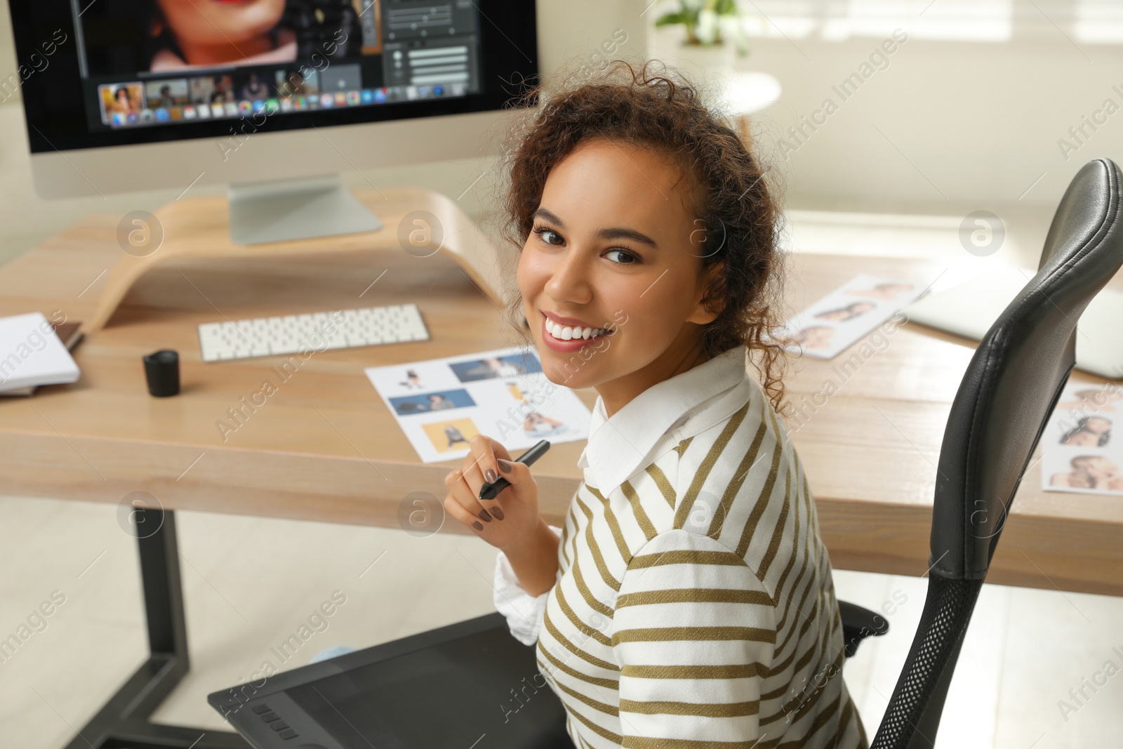 Photo of Professional African American retoucher working with graphic tablet at desk in office