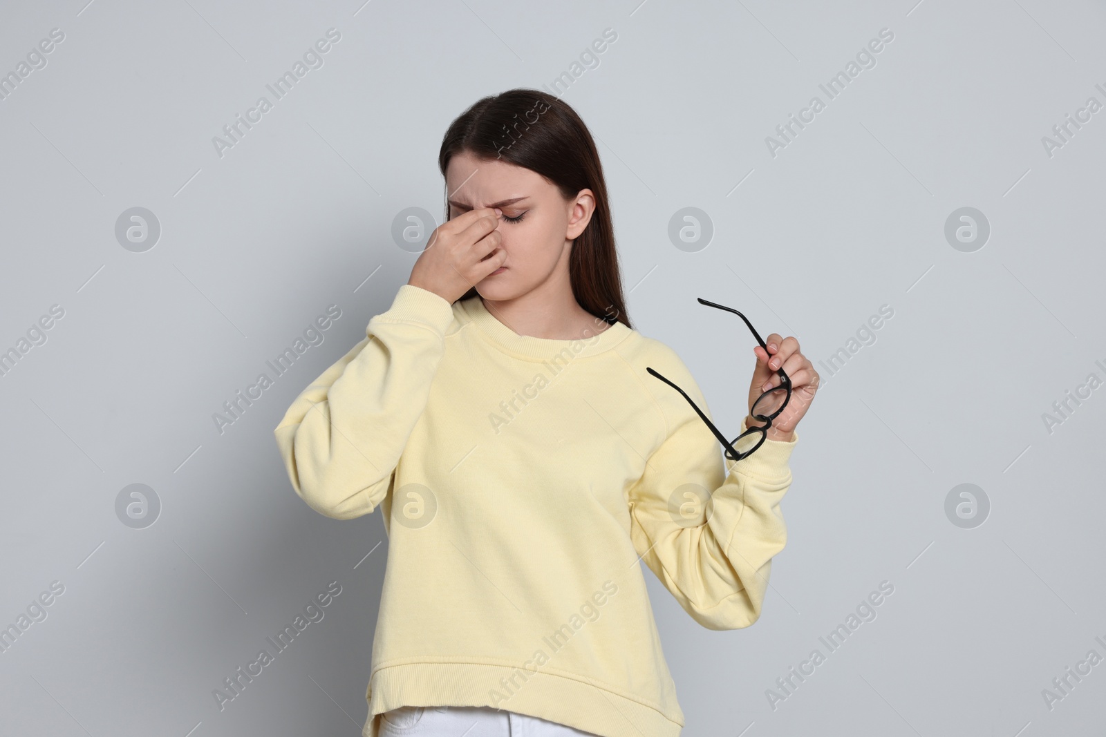 Photo of Young woman suffering from eyestrain on light background