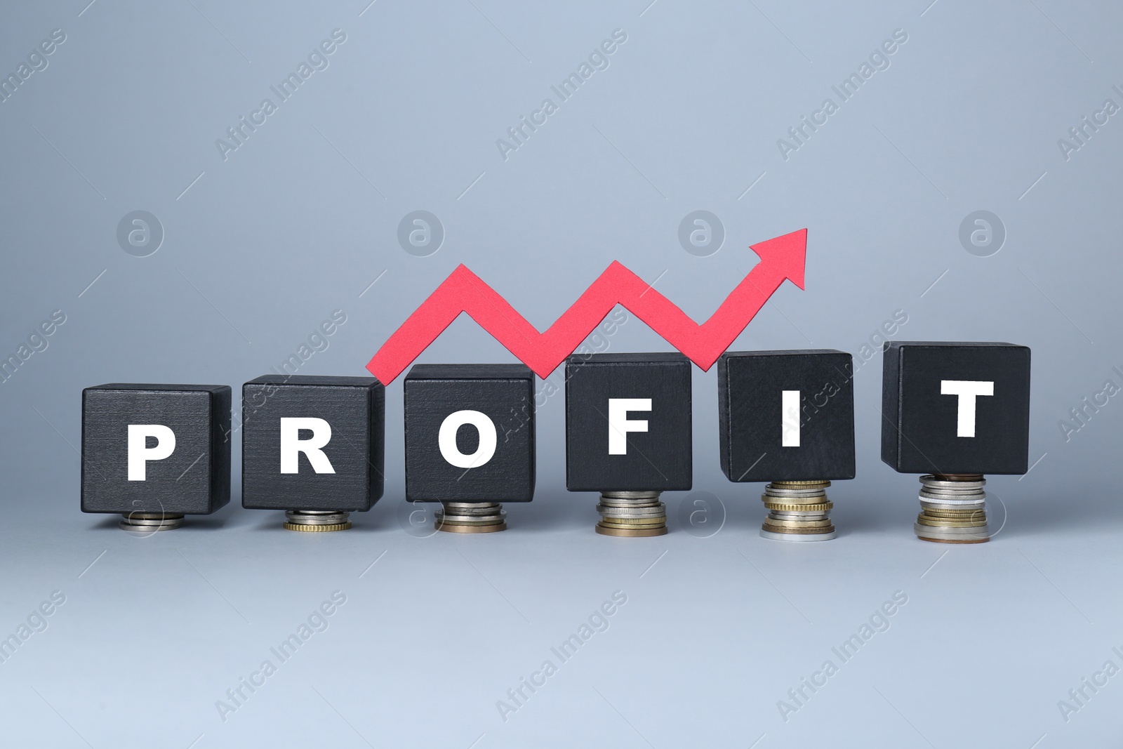 Photo of Black wooden cubes with word Profit and arrow on stacked coins against light grey background