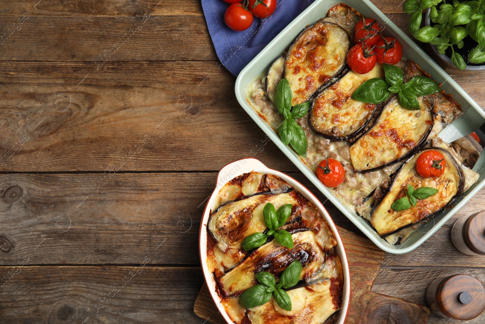 Photo of Delicious eggplant lasagna in baking dishes on wooden table, flat lay. Space for text