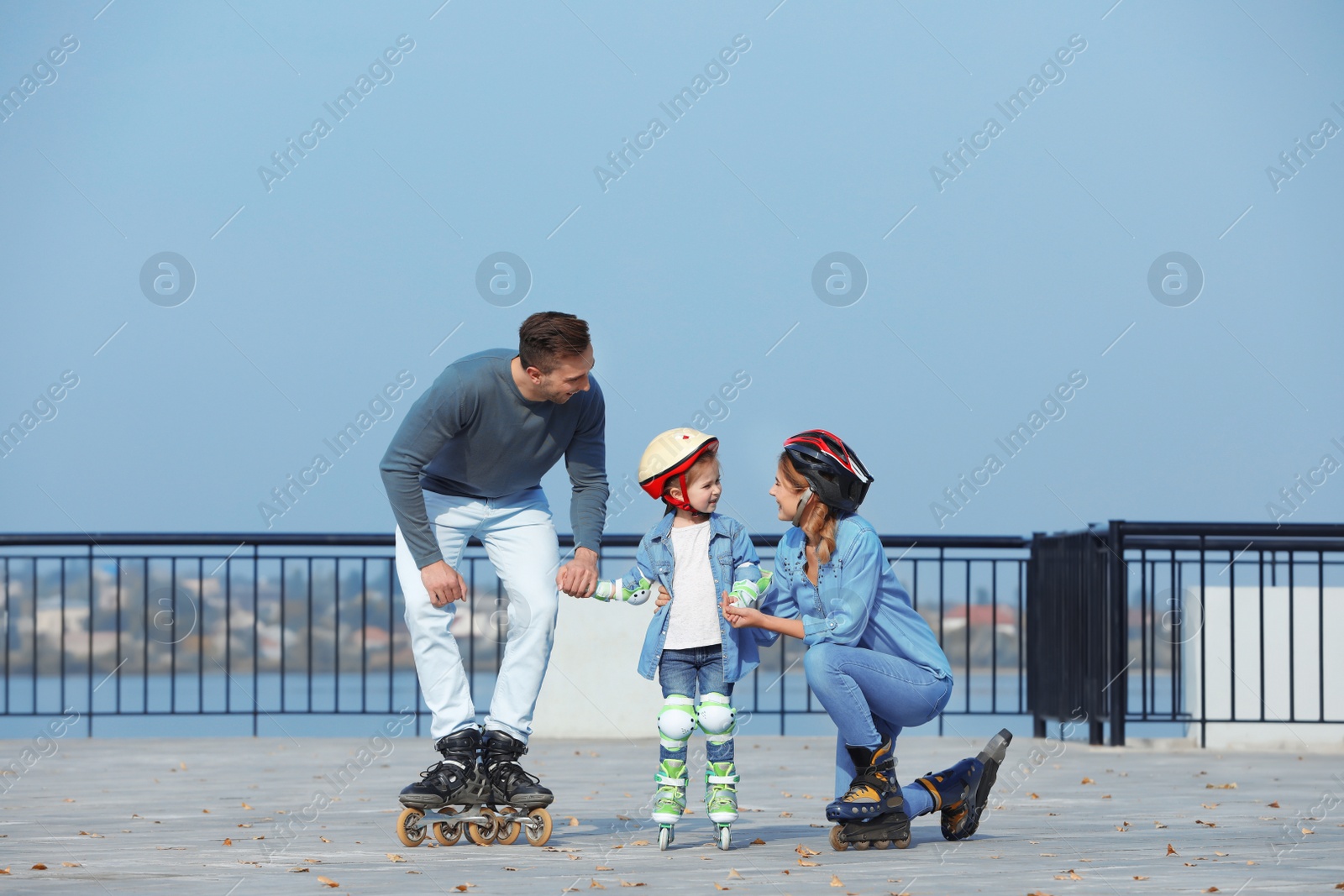 Photo of Happy family roller skating on embankment. Active leisure