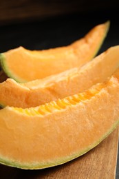 Photo of Slices of tasty fresh melon on wooden board, closeup