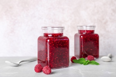 Photo of Jars with delicious raspberry jam on table