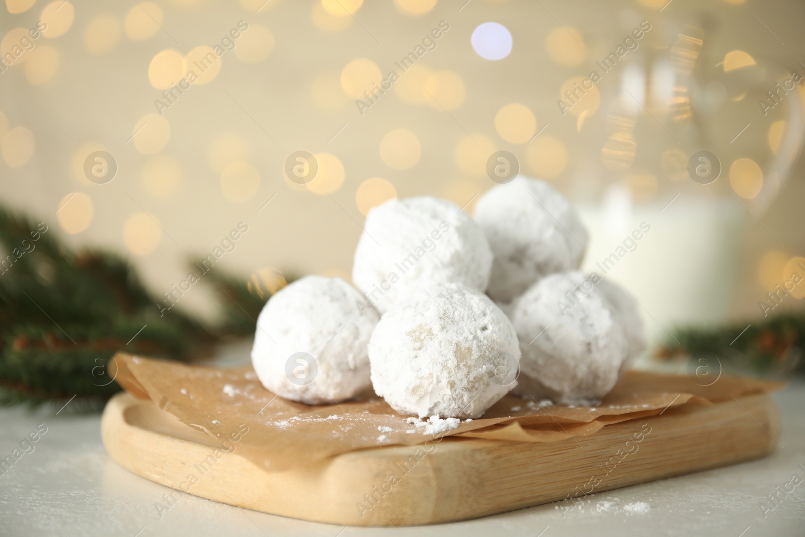 Photo of Christmas snowball cookies and fir tree branches on light table, closeup