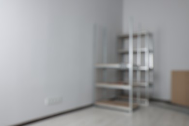 Photo of Blurred view of room with white walls and metal storage shelves