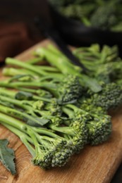 Fresh raw broccolini on wooden board, closeup. Healthy food