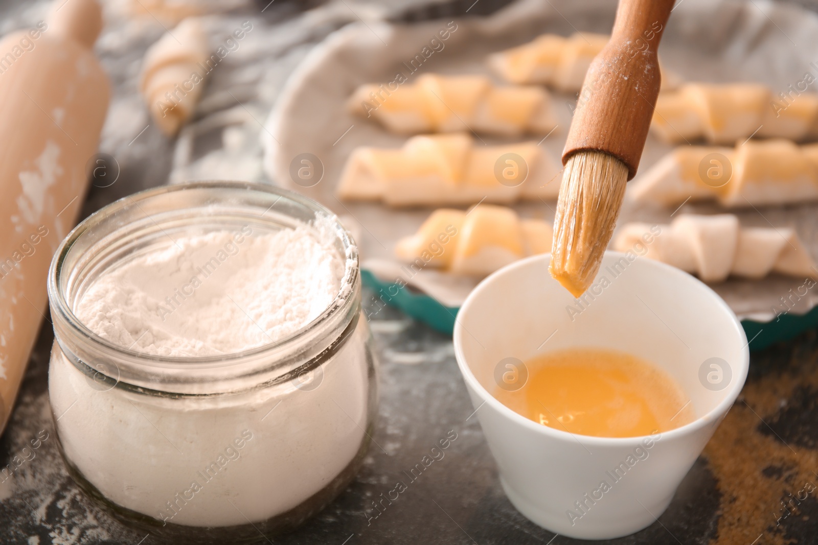 Photo of Spreading egg yolk on croissants, closeup