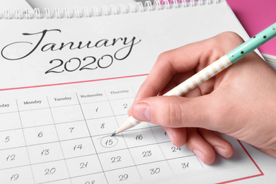 Woman marking date in calendar with pencil, closeup