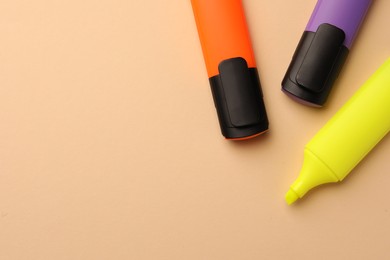 Bright color markers on beige background, flat lay. Space for text