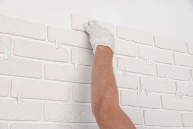 Photo of Professional builder installing new white decorative bricks on wall, closeup