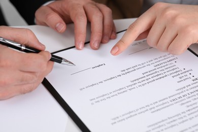 Photo of Businesspeople signing contract at white table, closeup of hands