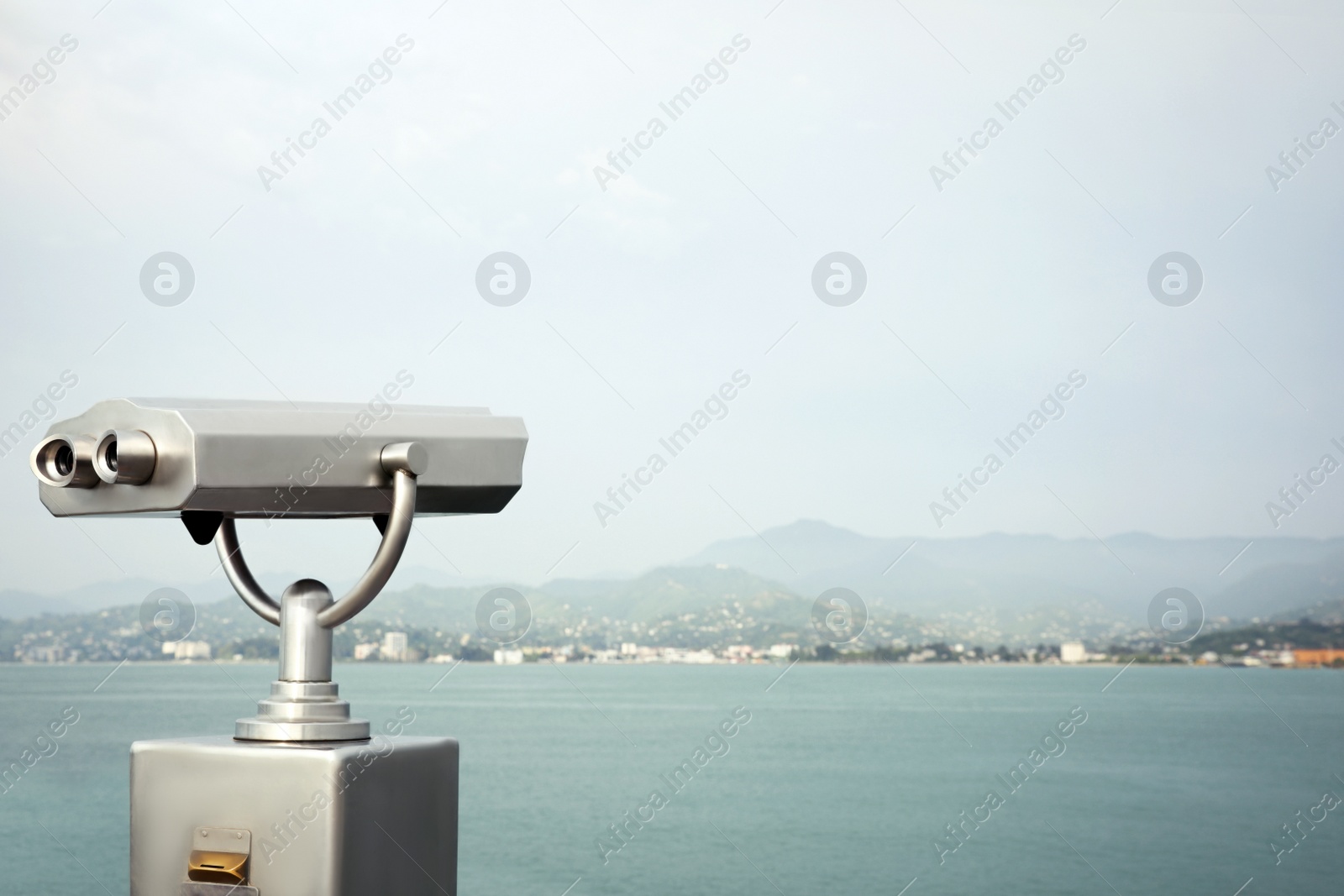 Photo of Metal tower viewer installed near sea, space for text. Mounted binoculars