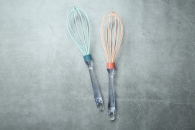 Two whisks on gray table, top view