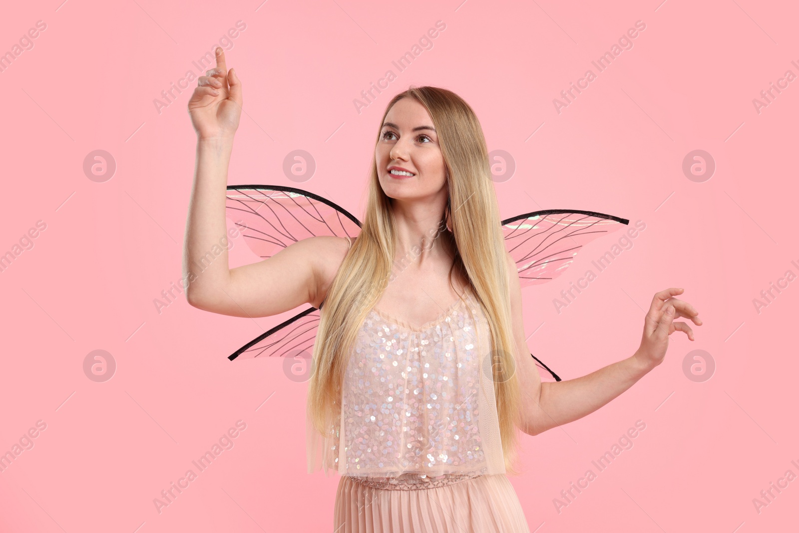 Photo of Beautiful girl in fairy costume with wings on pink background