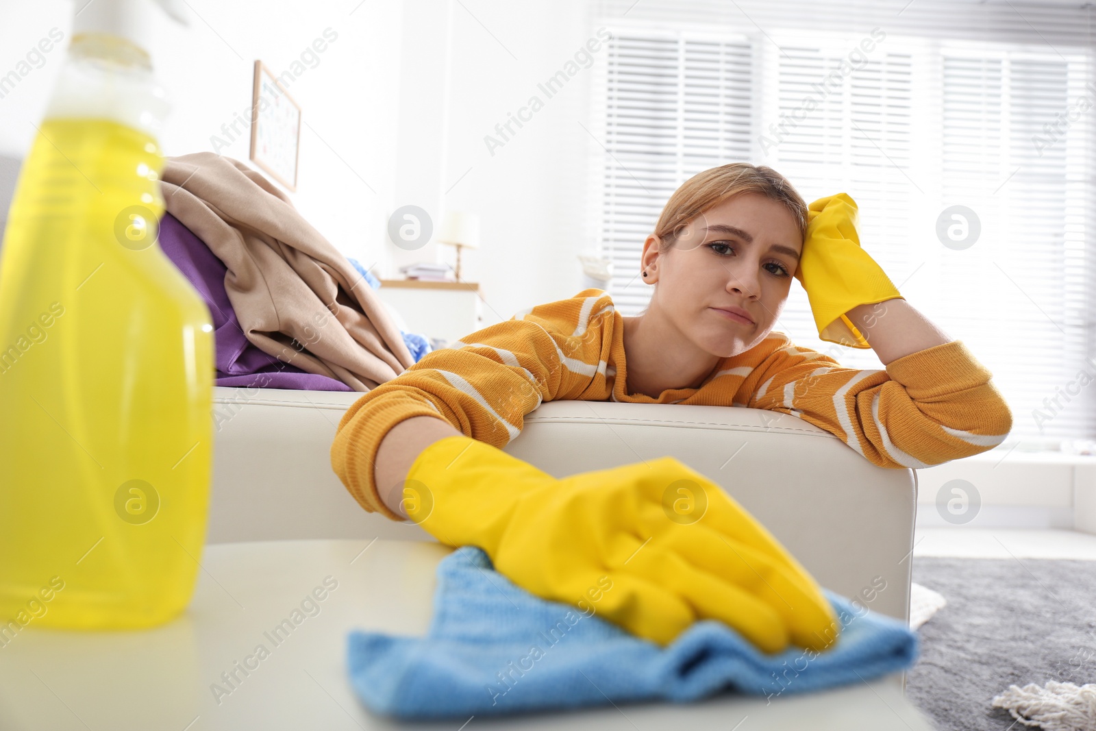 Photo of Lazy young woman wiping table at home. Cleaning and housework