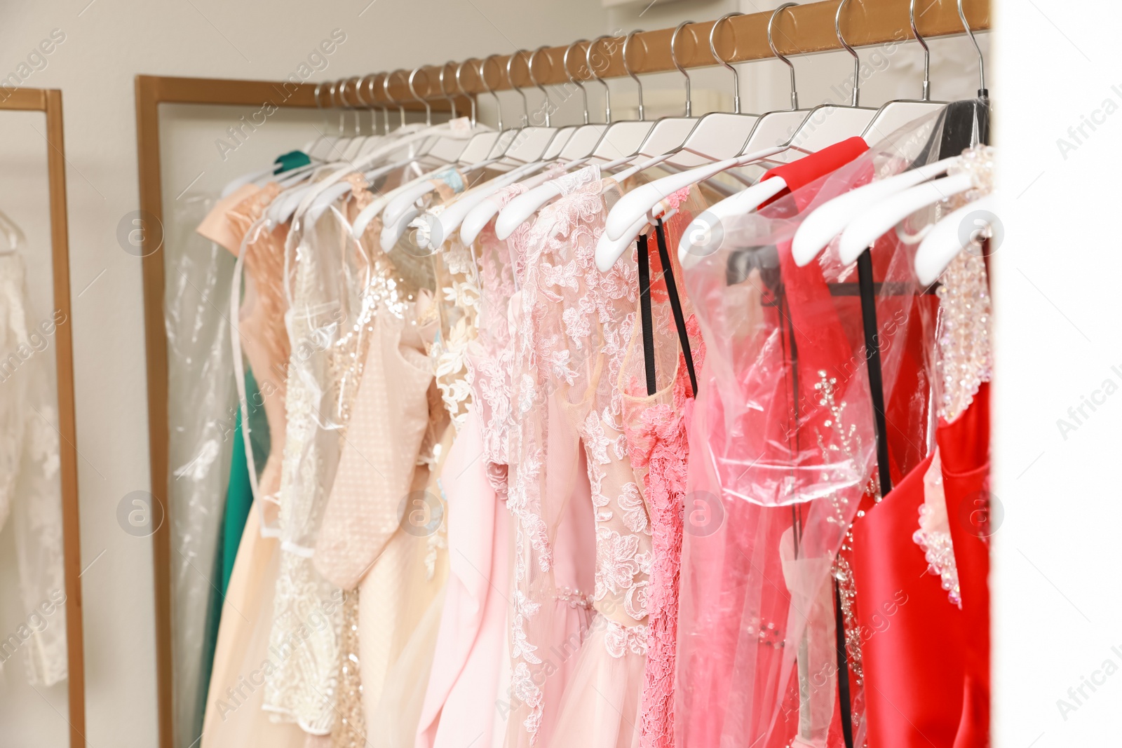 Photo of Different beautiful dresses on hangers in rental clothing salon