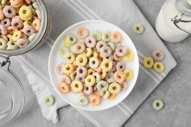 Photo of Tasty colorful cereal rings and milk in bowl on grey table, flat lay