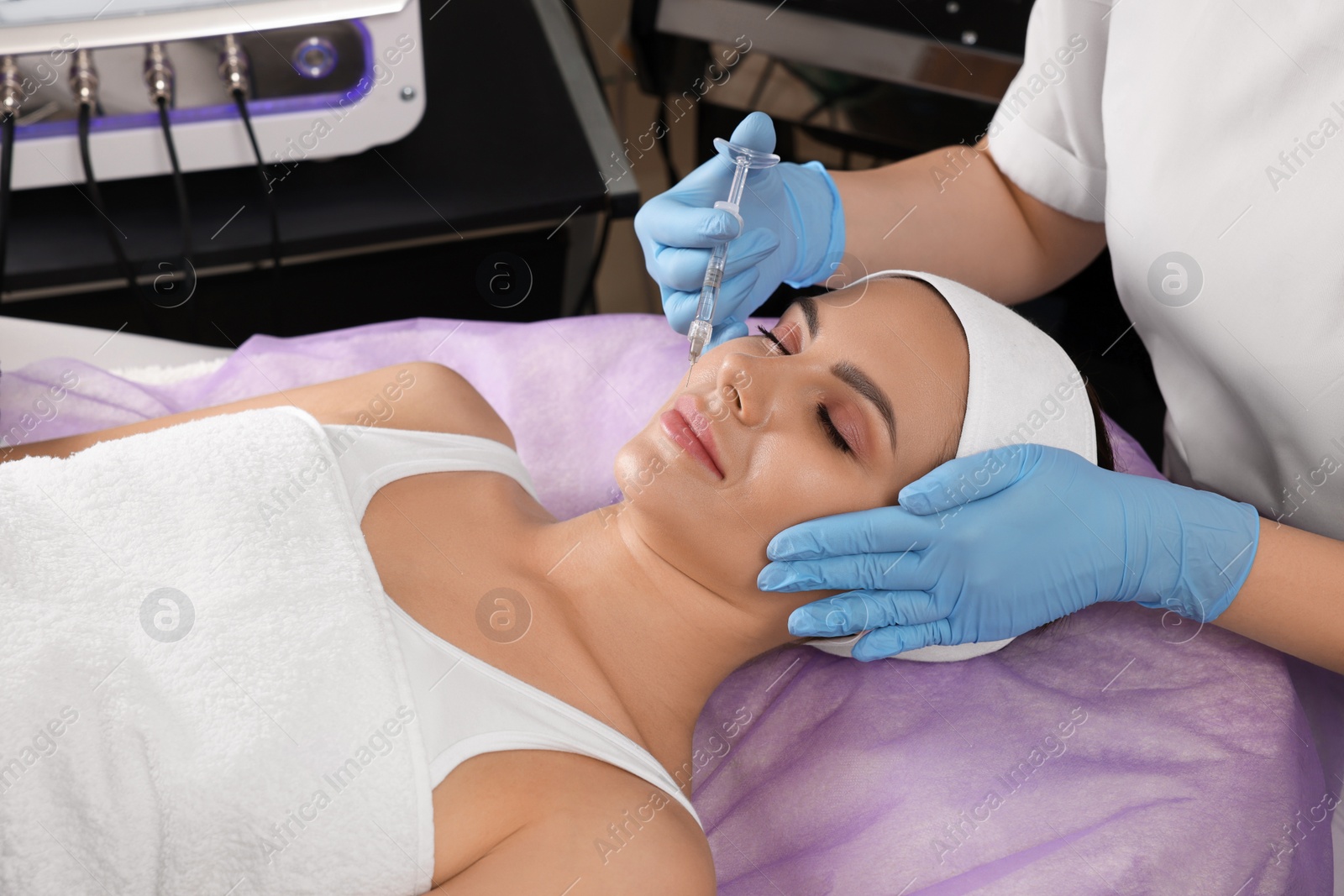 Photo of Young woman getting facial injection in beauty salon. Cosmetic procedure