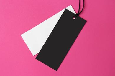 Tags with space for text on pink background, top view