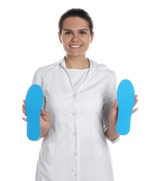 Photo of Beautiful female orthopedist showing insoles on white background