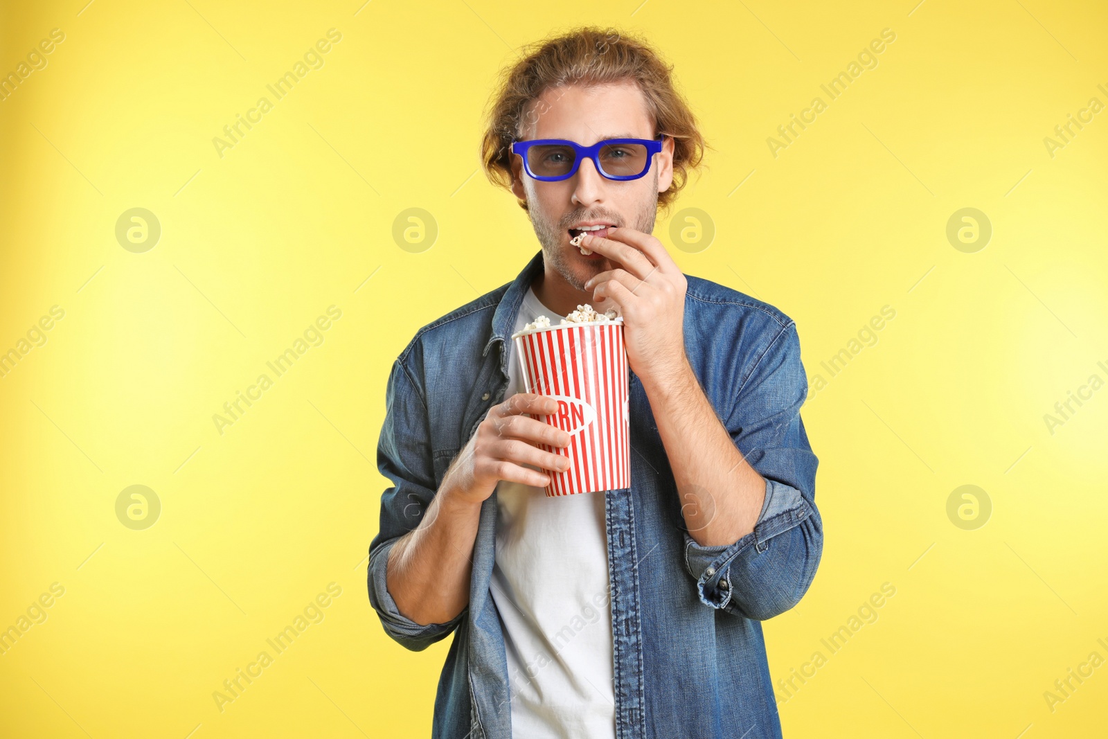 Photo of Man with 3D glasses and popcorn during cinema show on color background