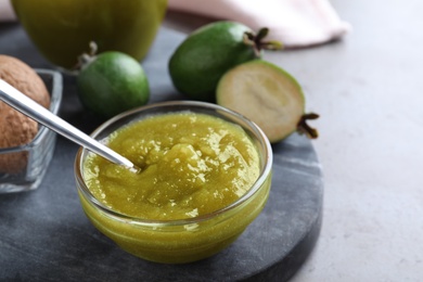 Photo of Feijoa jam in glass bowl on grey table, closeup