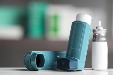 Photo of Asthma inhalers on table against blurred background. Space for text