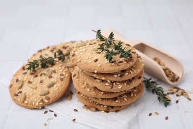 Photo of Cereal crackers with flax, sesame seeds and thyme on white tiled table, closeup
