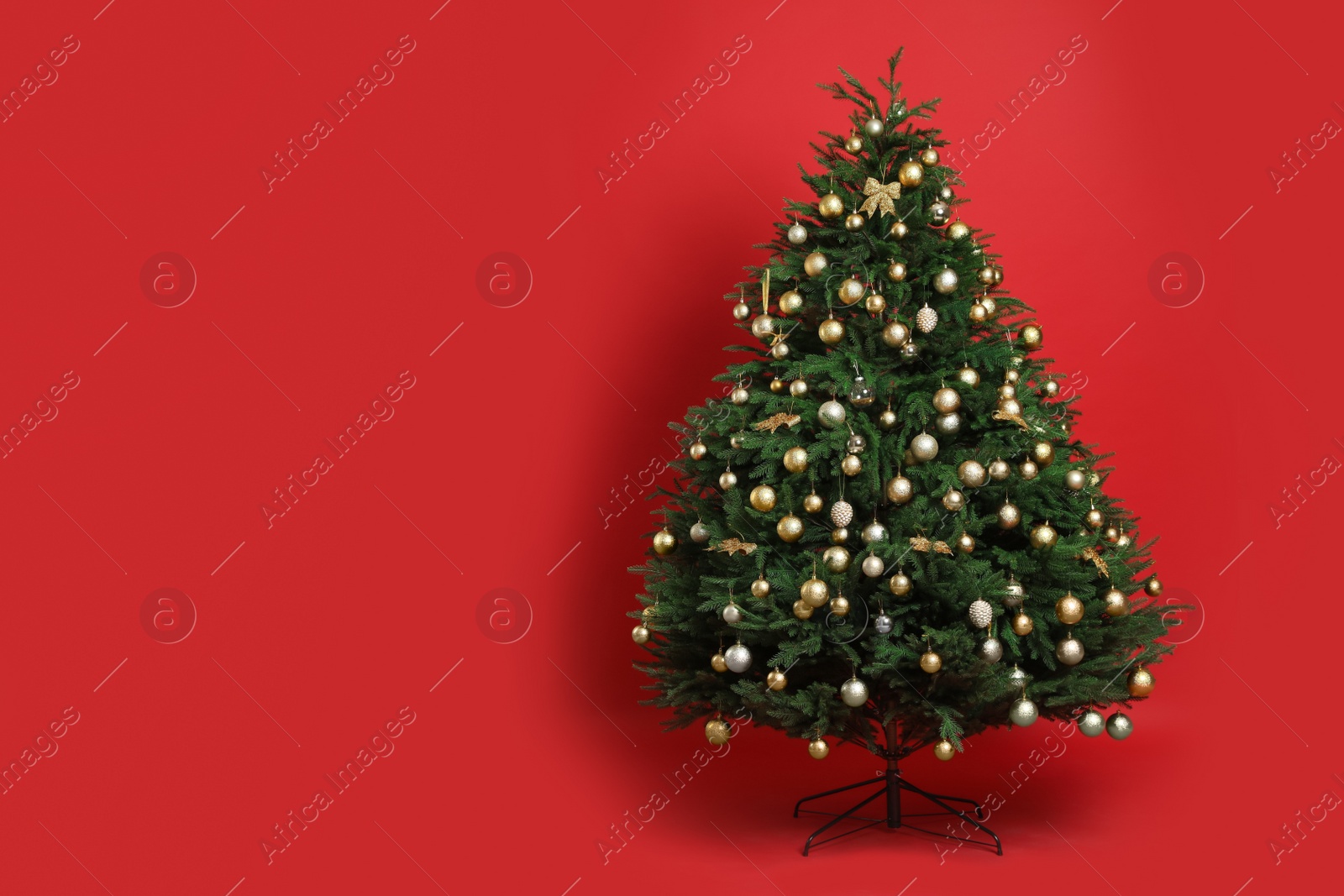 Photo of Beautifully decorated Christmas tree on red background, space for text