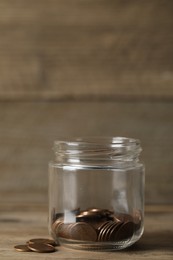 Glass jar with coins on wooden table