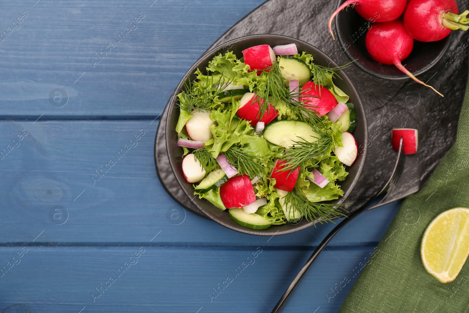 Photo of Tasty salad with radish in bowl on blue wooden table, flat lay. Space for text