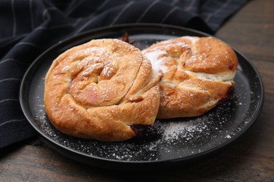 Photo of Delicious rolls with sugar powder on wooden table, closeup. Sweet buns