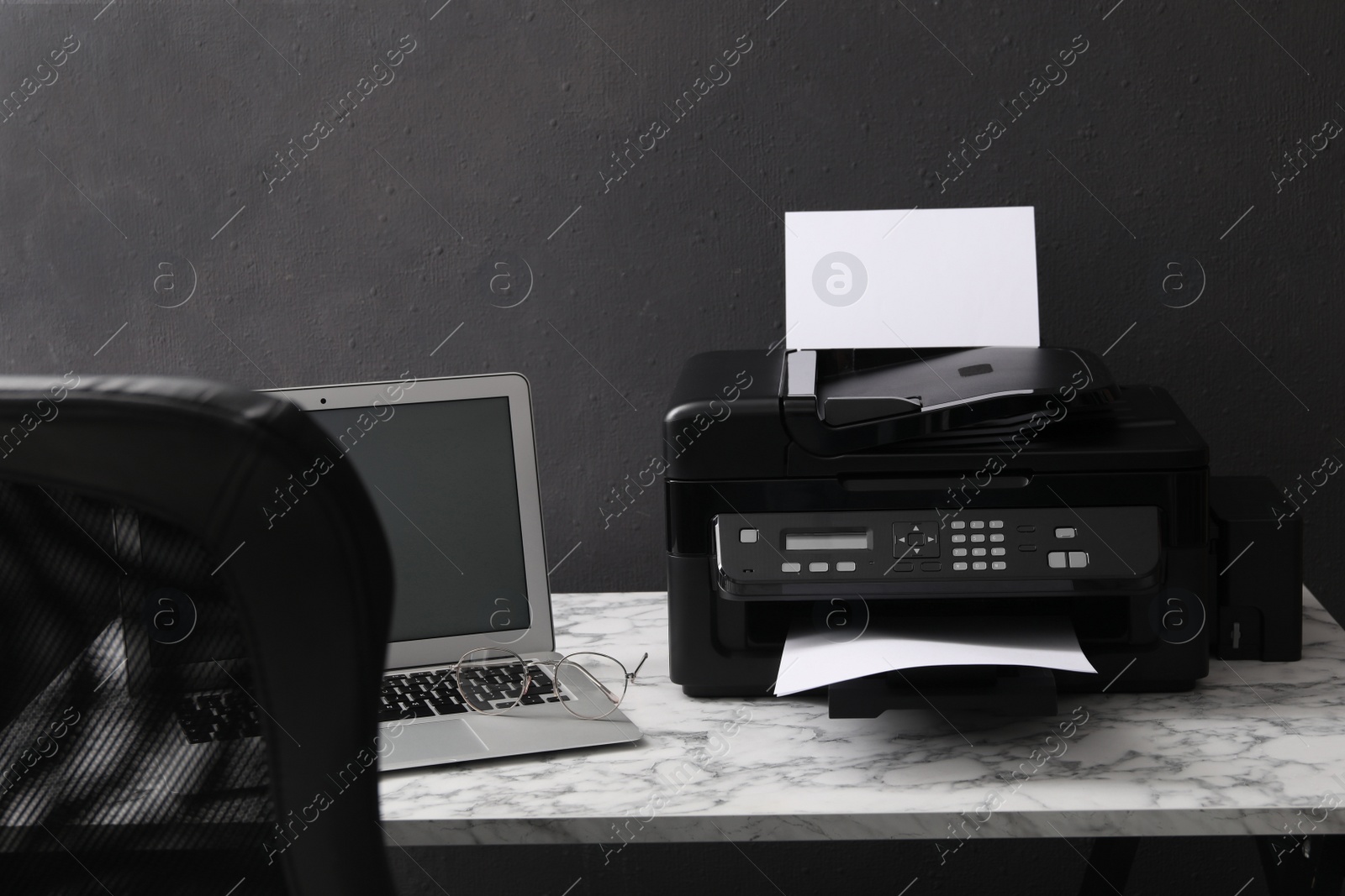 Photo of Modern printer and laptop on white marble table