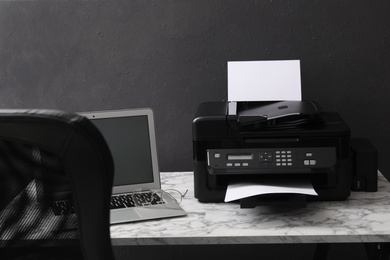 Photo of Modern printer and laptop on white marble table