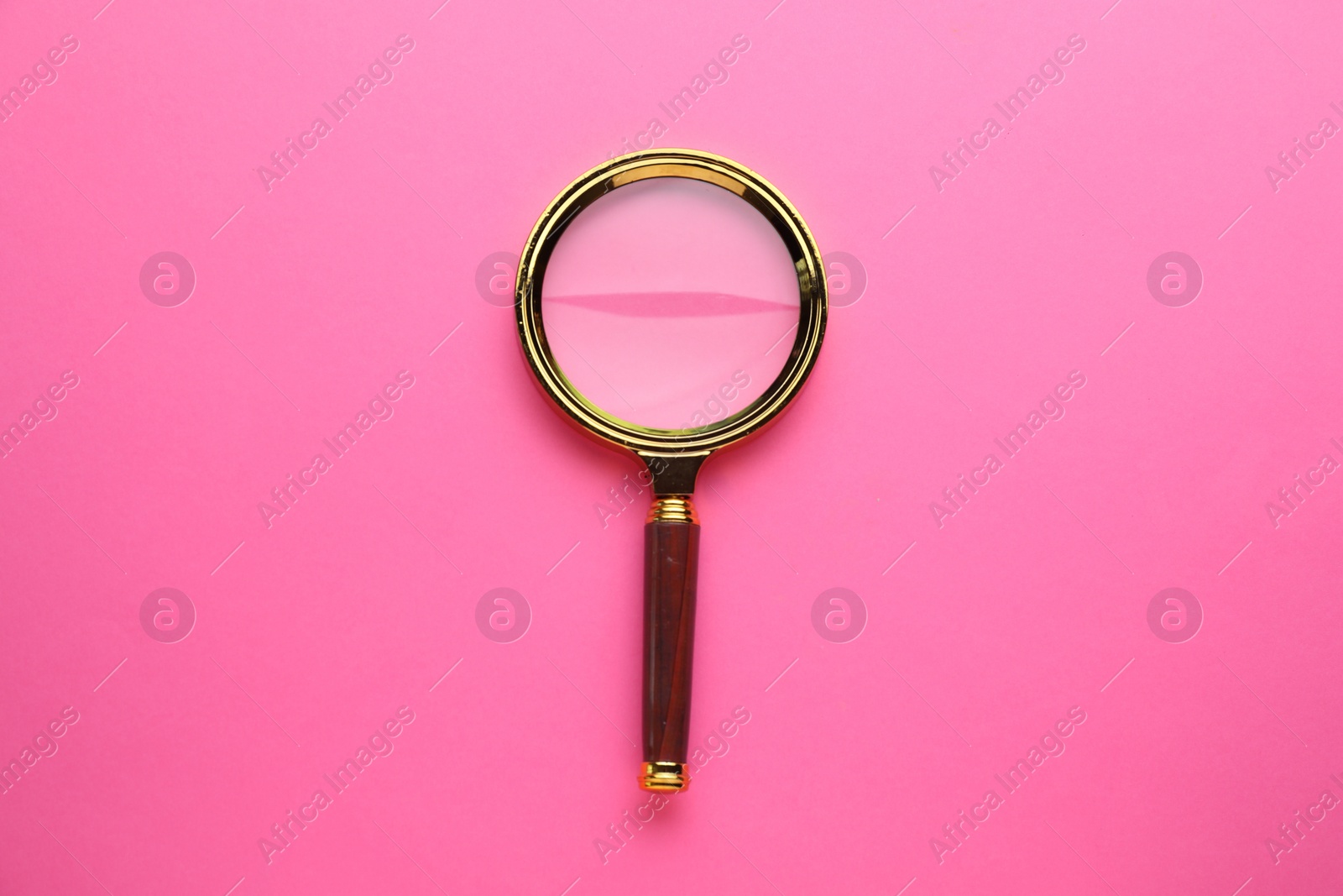 Photo of Magnifying glass on pink background, top view