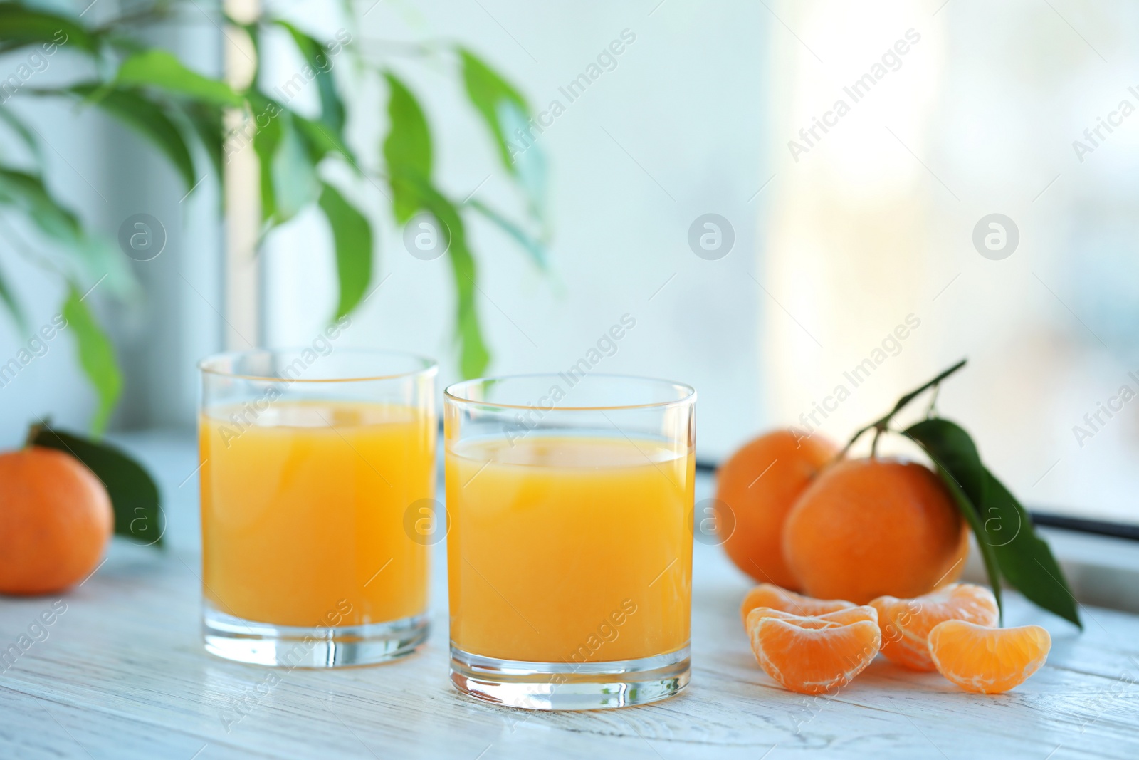 Photo of Glasses of fresh tangerine juice and fruits on white wooden table