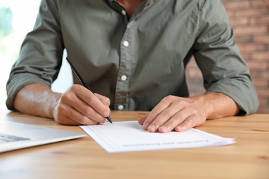 Male notary signing document at table in office, closeup