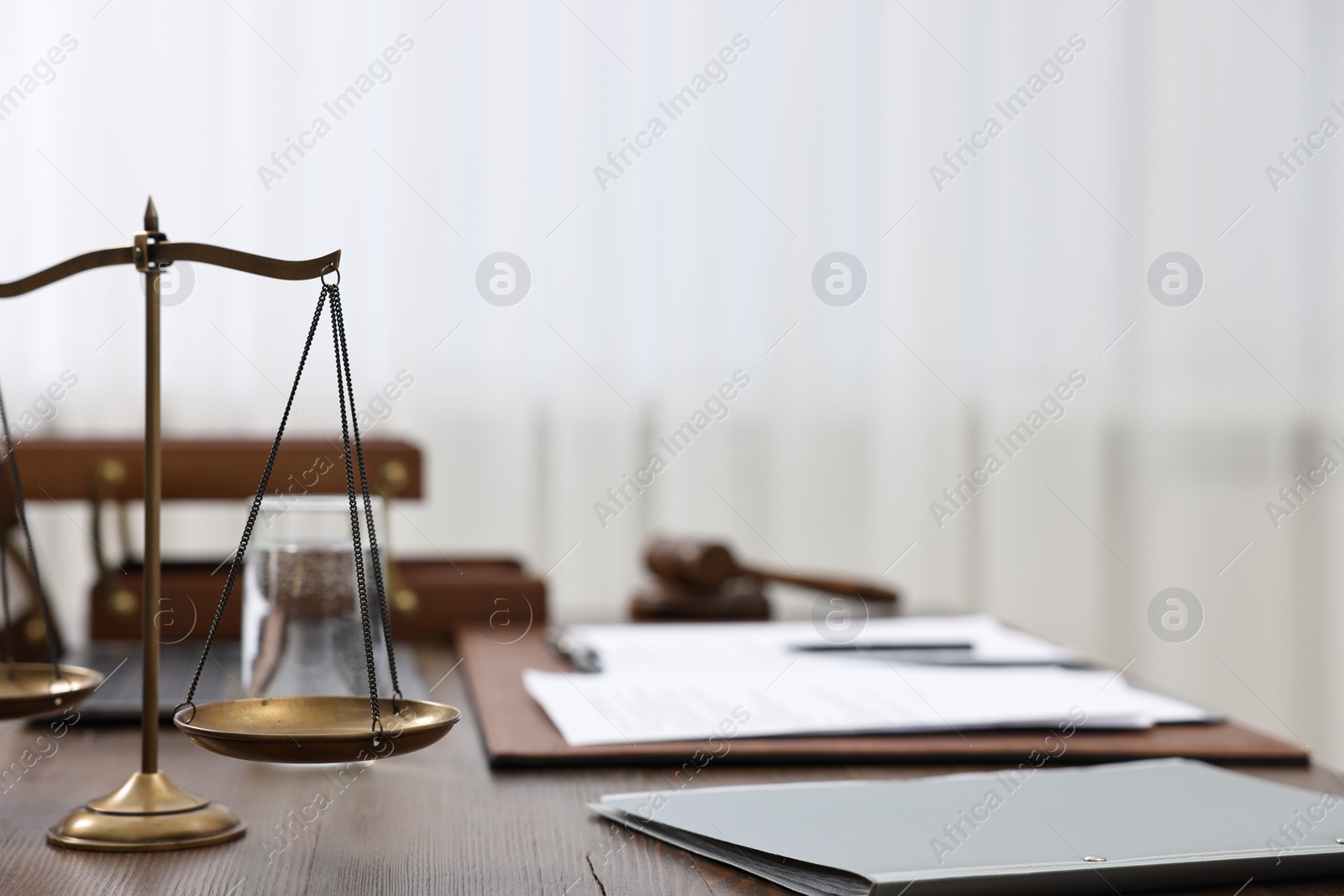 Photo of Lawyer's workplace. Scales of justice, folder and documents on wooden table indoors, space for text