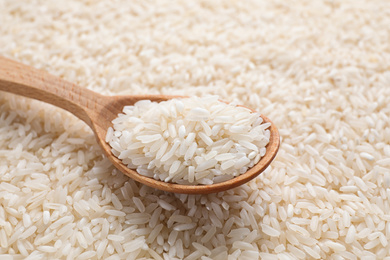 Photo of Pile of polished rice and wooden spoon, closeup