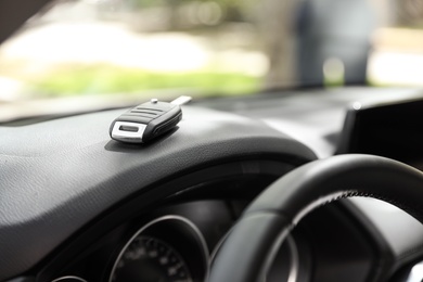 Car key on dashboard in auto against blurred background