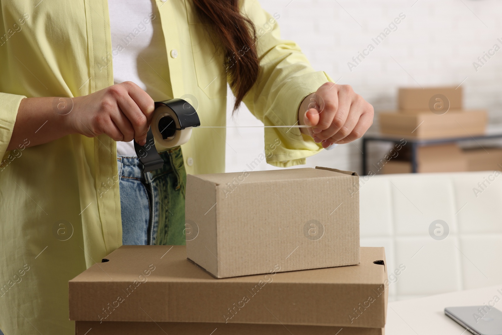 Photo of Seller packing cardboard box in office, closeup