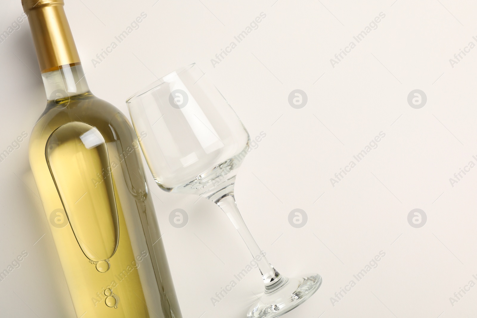 Photo of Bottle of expensive white wine and wineglass on light background, top view. Space for text