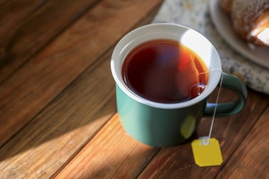 Photo of Tea bag in cup on wooden table, closeup. Space for text