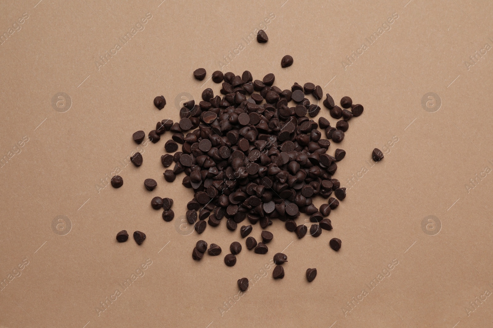 Photo of Pile of delicious chocolate chips on brown background, top view