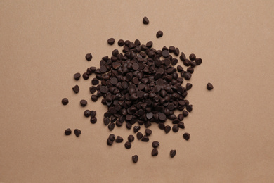 Photo of Pile of delicious chocolate chips on brown background, top view