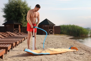 Man pumping up SUP board on river shore