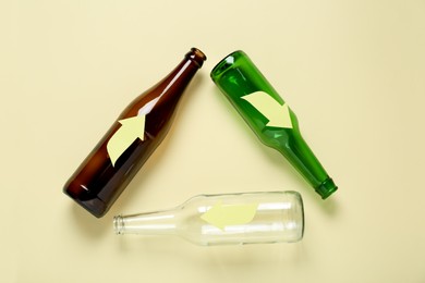 Photo of Recycling symbol made of empty glass bottles on beige background, flat lay