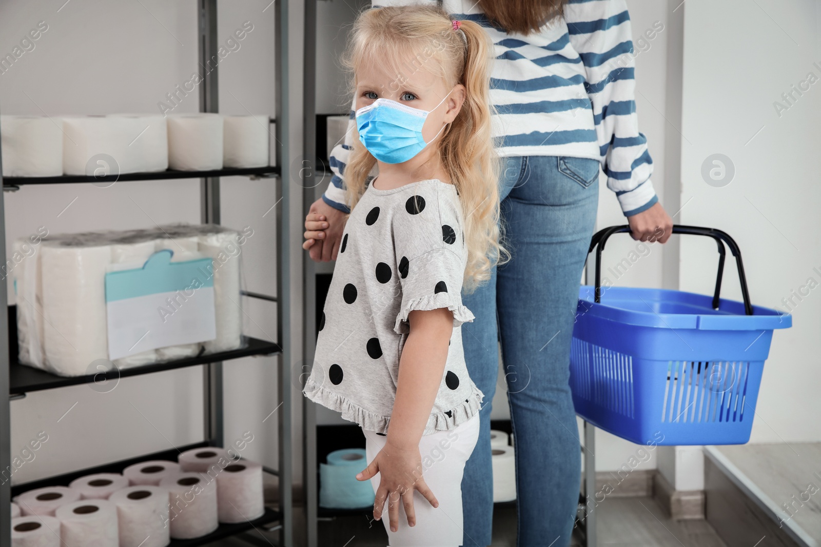 Image of Little girl with medical mask and mother buying toilet paper in shop