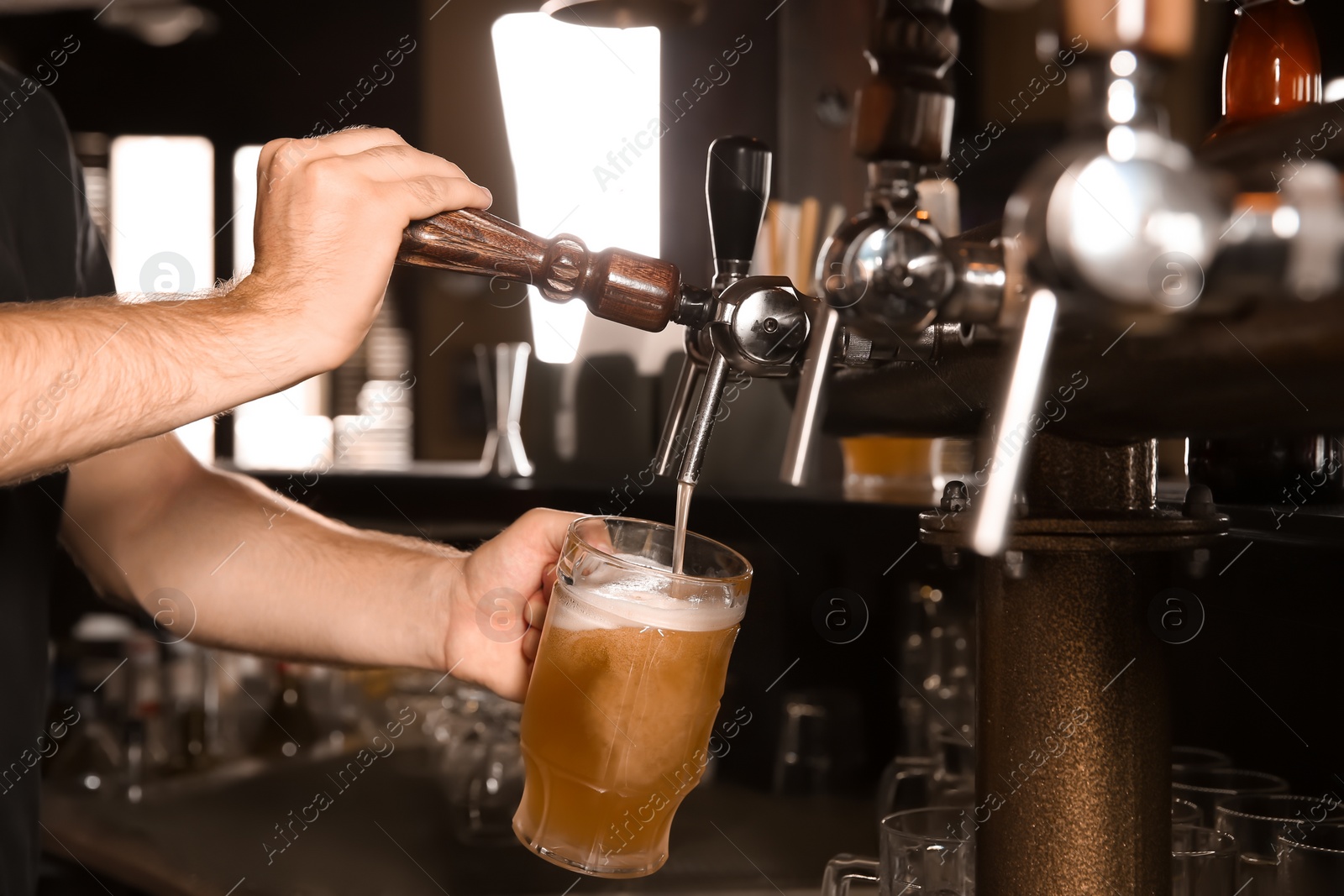 Photo of Bartender pouring beer from tap into glass in bar, closeup